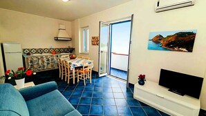 A compact living space with a dining area, a sofa, a TV, and a kitchen. - Seaview 3-room apartment- 3 min by car from the beach (Capo d'Orlando)