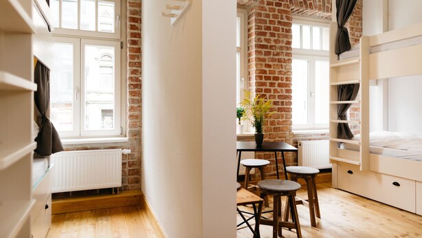 A room with exposed brick walls, white furniture, and a window with curtains.