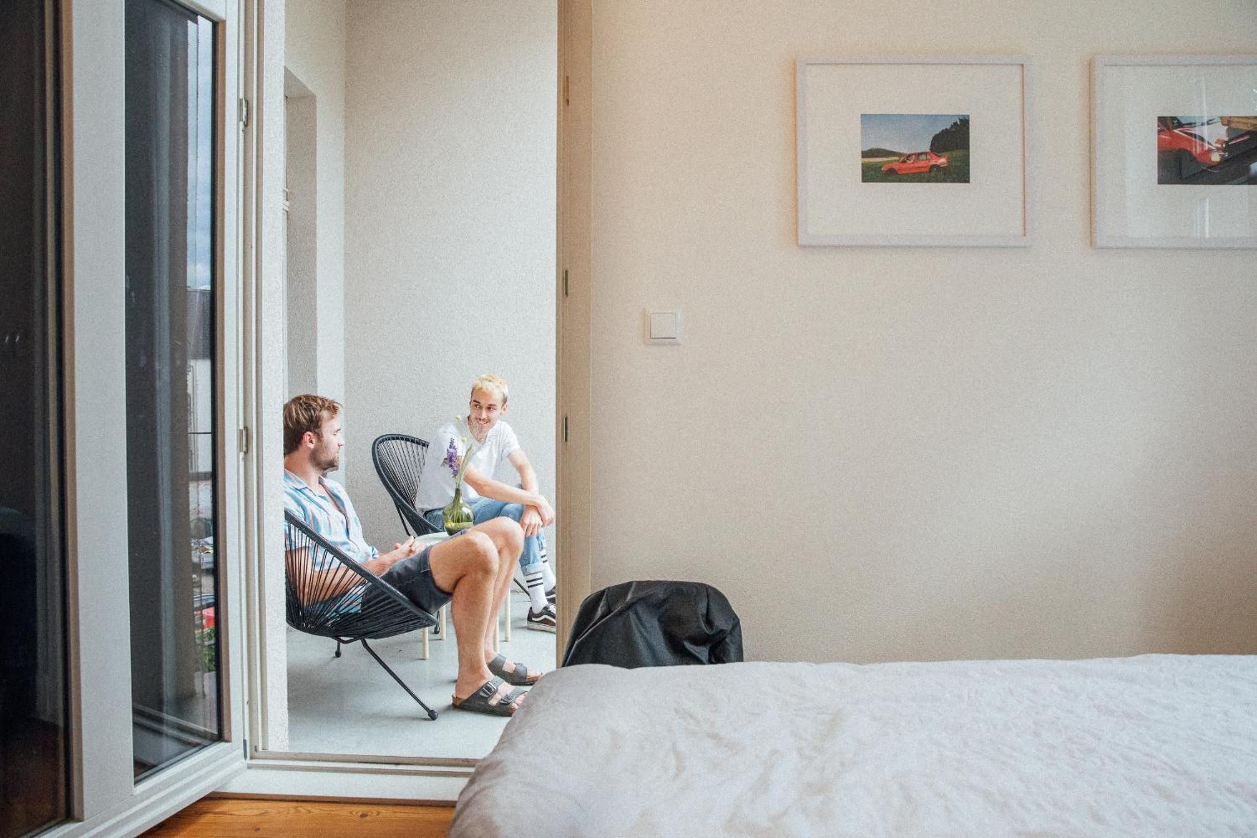 Une pièce avec un lit, deux chaises, une fenêtre et une porte.