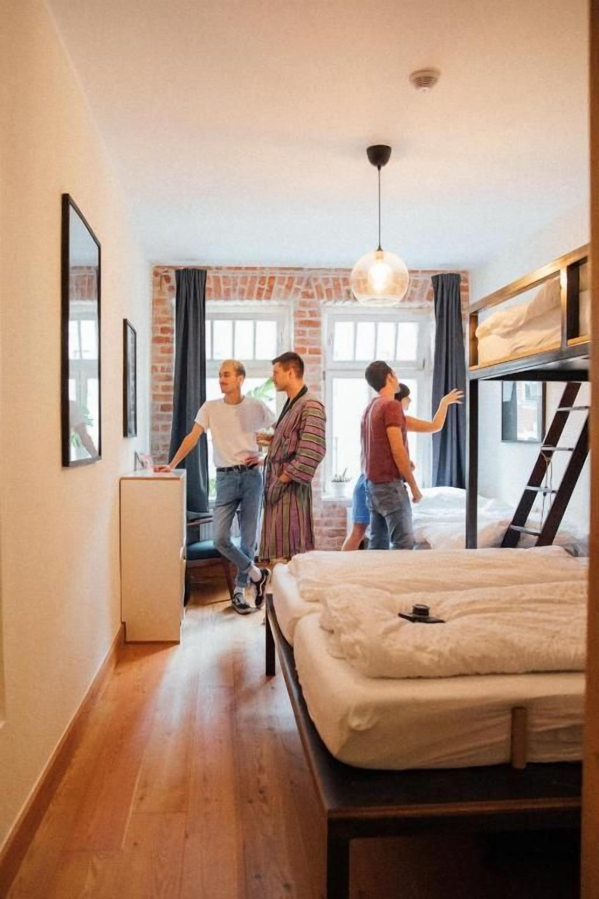 Una habitación con literas, un escritorio y una lámpara colgante.
