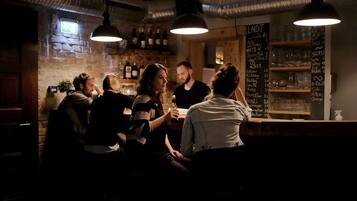 Un bar con pared de piedra, luces colgantes y una pizarra con el menú.