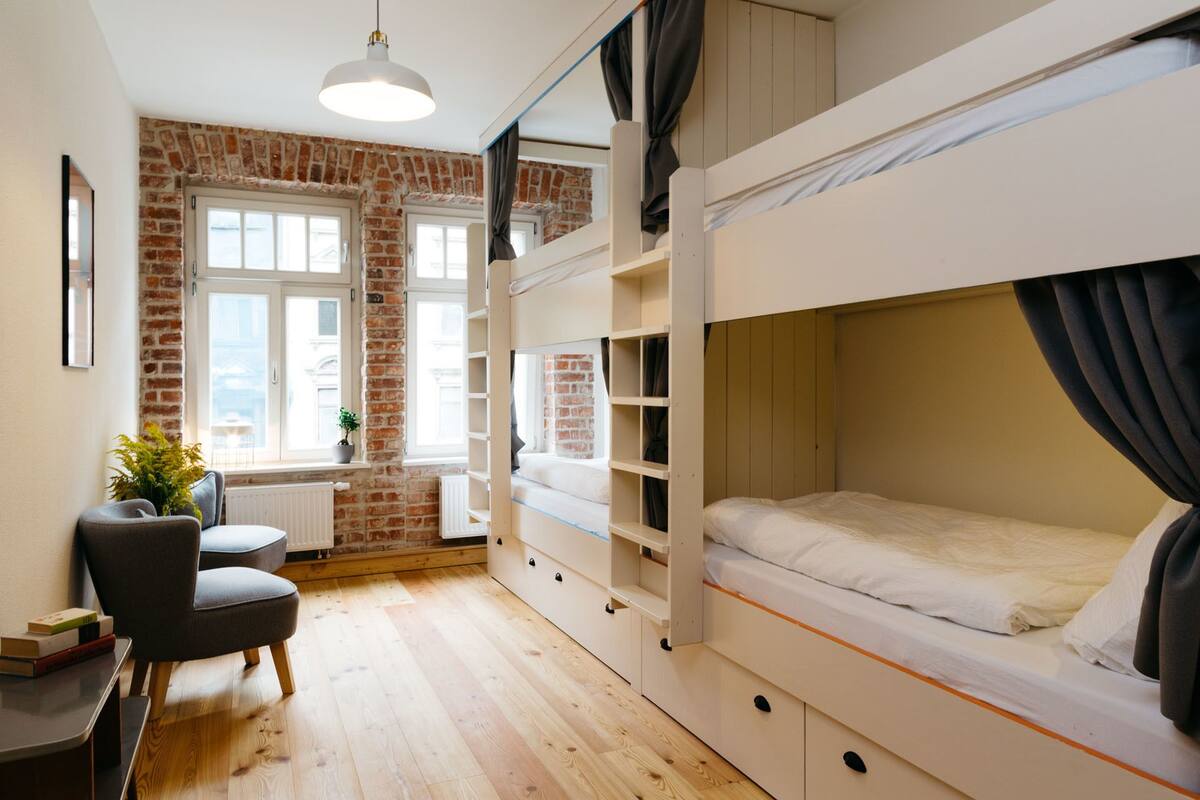 A bunk bed room with a brick wall, a desk, and a chair.