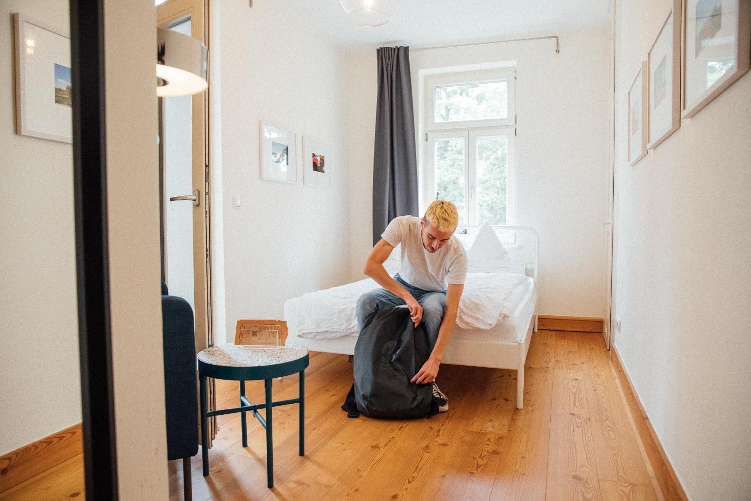 Una stanza arredata con un letto, un tavolino, una sedia e una finestra con tende.