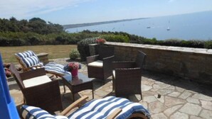 Eine Terrassenanlage im Freien mit Korbmöbeln und Blick auf das Meer.