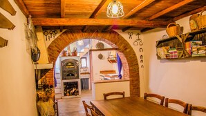 A rustic dining area with a wooden table and chairs, an arched brick wall, and a shelf with books and baskets. - House with private pool. Quiet Location. Fenced/secured pool area (Santa Restituta)