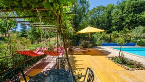 A wooden deck with a table and chairs, a hammock, and a yellow umbrella. - House with private pool. Quiet Location. Fenced/secured pool area (Santa Restituta)