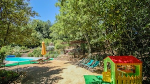 A pool area with lounge chairs and a small playhouse. - House with private pool. Quiet Location. Fenced/secured pool area (Santa Restituta)