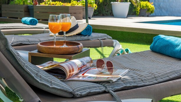 A sun lounger with a magazine, sunglasses, and two glasses of orange juice. - Holiday Villa in Seville Countryside. Private pool, a.a., tv sat, free wifi (Lantejuela, La)