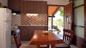 Una cucina funzionale con mobili in legno, zoccolo piastrellato e zona pranzo con tavolo e sedie in legno.