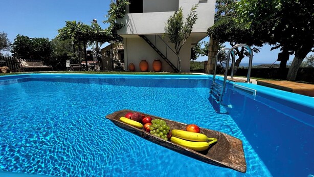 Una piscina con un vassoio di legno pieno di frutta.