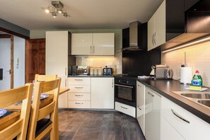 A modern kitchen with white cabinetry, a built-in oven, and a coffee machine.