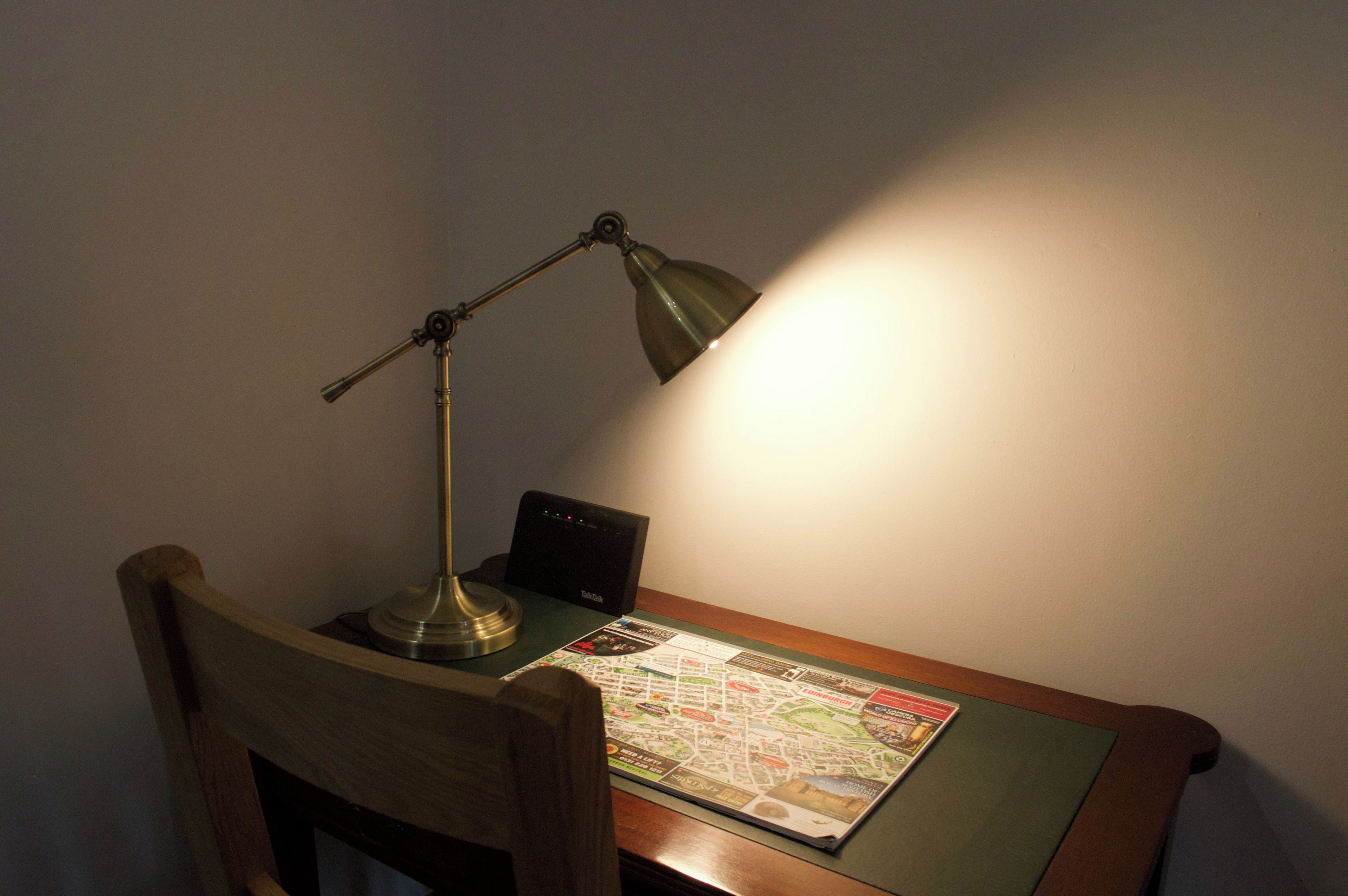 A desk with a map, a lamp, and a small electronic device.