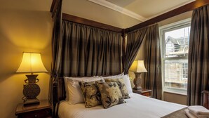 Une chambre d’hôtel avec un grand lit, deux lampes de chevet, une fenêtre avec des rideaux et une vue sur l’extérieur.