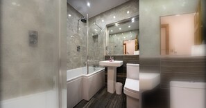 A modern bathroom with a glass-enclosed shower, a standalone bathtub, a pedestal sink, and a toilet.