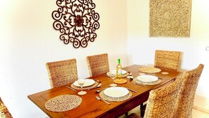 A dining table set with white plates, cutlery, and wine glasses, surrounded by wicker chairs. - Splendid, luxurious beach holiday house near fishing villages. A/C pool** (Nuevo Portil)