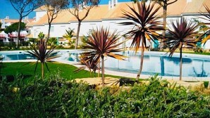 A pool area with palm plants and a building in the background. - Splendid, luxurious beach holiday house near fishing villages. A/C pool** (Nuevo Portil)