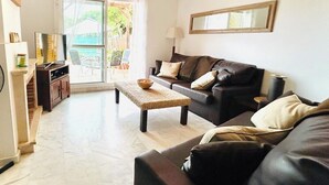 A living room with a sofa, a coffee table, a TV, and a fireplace. - Splendid, luxurious beach holiday house near fishing villages. A/C pool** (Nuevo Portil)