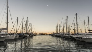 Ein Yachthafen mit mehreren Segelbooten, ruhigem Wasser und blauem Himmel.