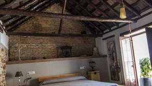 Ein rustikales Schlafzimmer mit freiliegenden Holzbalken, einem Holzbettgestell, einem Nachttisch und einer Hängelampe.