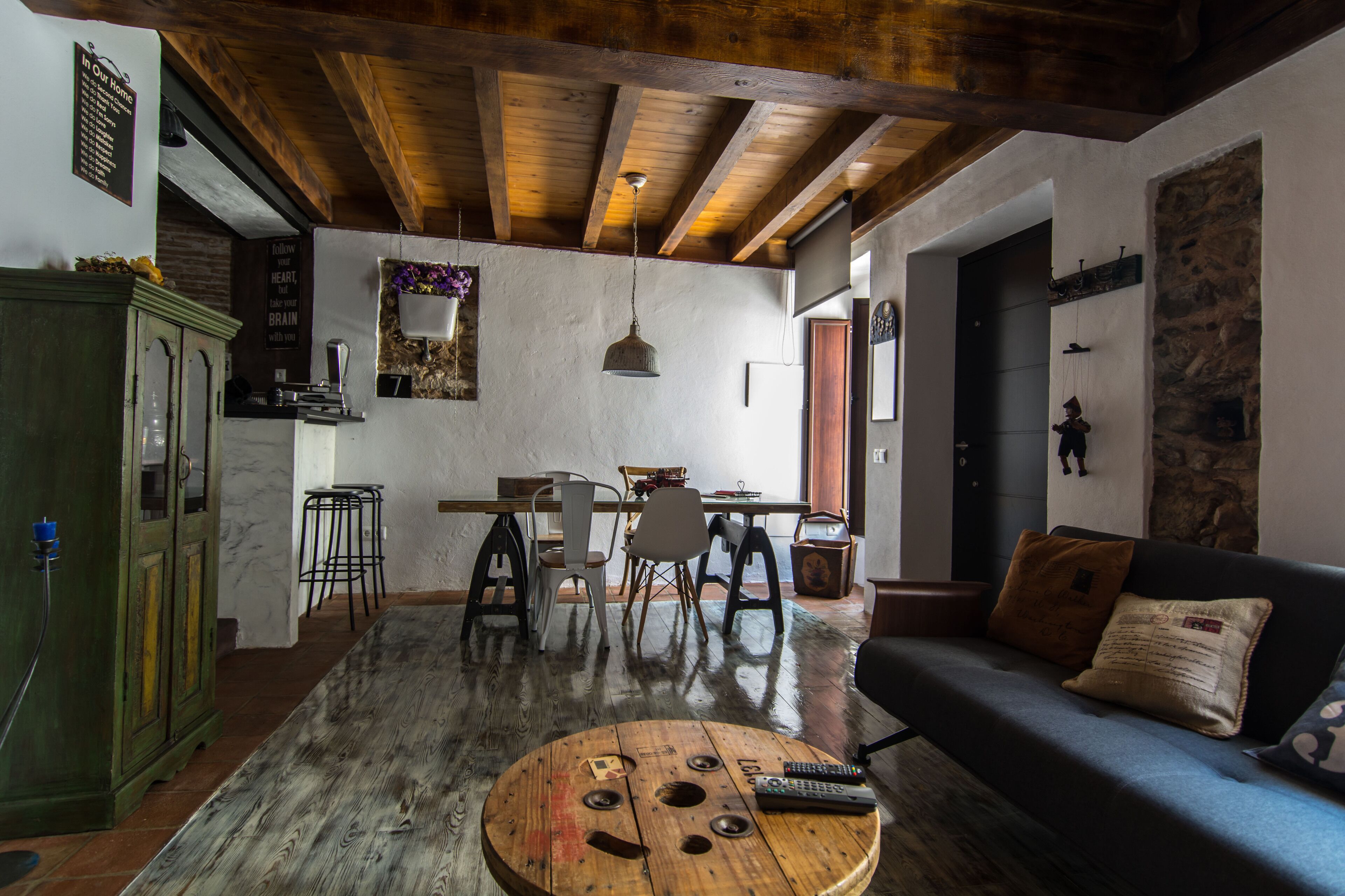 Ein rustikales Wohnzimmer mit Holzbalkendecke, einem runden Couchtisch und einer Couch mit Kissen.