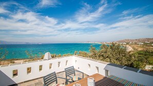 Une terrasse avec une table et des chaises donnant sur une vue de la côte.