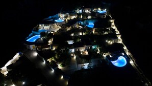 Vue aérienne d’un complexe hôtelier à plusieurs étages, doté de nombreuses piscines et d’espaces extérieurs bien éclairés.
