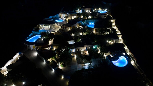 Vue aérienne d’un complexe hôtelier à plusieurs étages, doté de nombreuses piscines et d’espaces extérieurs bien éclairés.