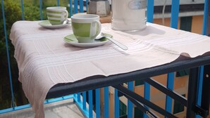 Ein Balkon mit Tisch für zwei, einer Kaffeekanne und einem Thermosbehälter.
