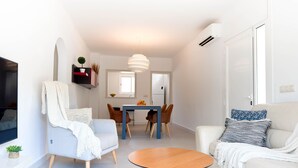 Una sala moderna con sofá, sillón, mesa de comedor y una pequeña mesa redonda.