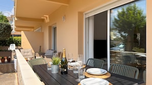 Un espacio de comedor al aire libre con una mesa dispuesta para dos personas, una botella de champán y vistas del entorno.