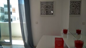 Ein modernes Zimmer mit Balkon, zwei gerahmte Wandkunstwerke und ein Tisch mit zwei roten Kerzen.