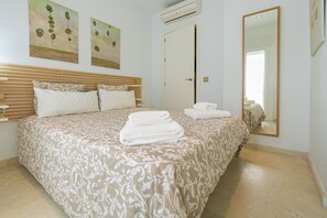 A hotel room with a bed, two paintings, an air conditioner, a door, and a mirror. - TOWER. Walking distance to La Caleta. Ascensor.WIFI  (cadiz)