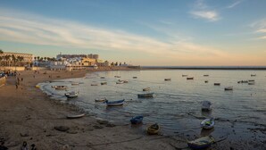 Une plage avec des bateaux, un rivage sablonneux et des bâtiments en arrière-plan.