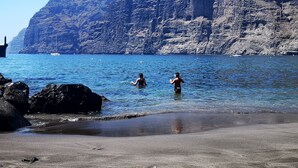 Ein Strand mit felsigen Klippen und ruhigem Wasser.