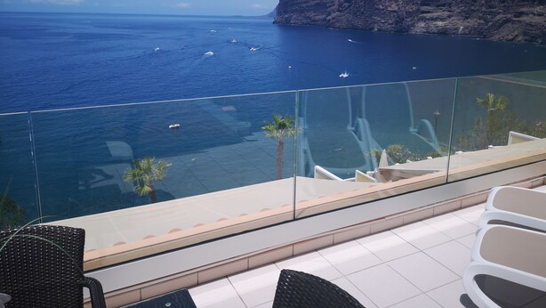 Ein Balkon mit Blick auf das Meer und eine felsige Klippe.