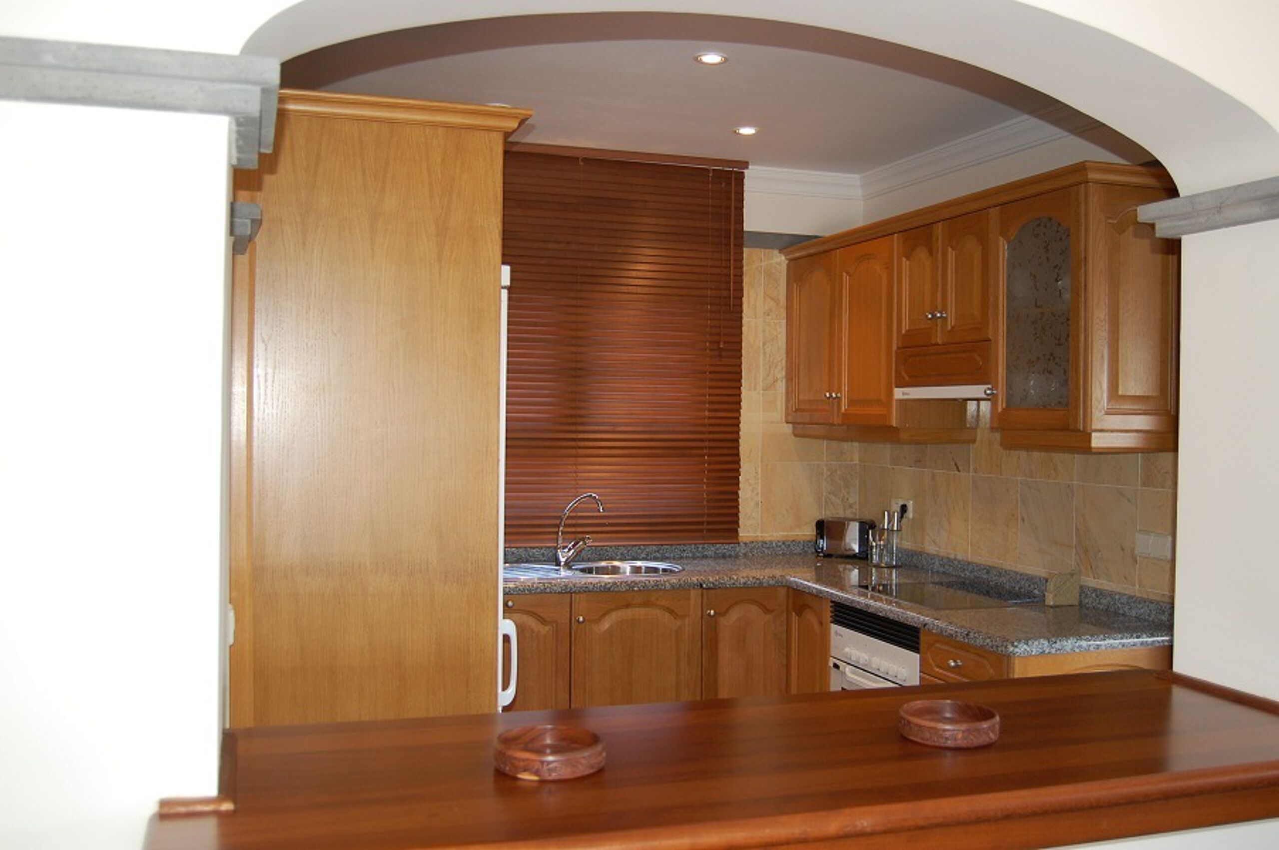 A kitchen with wooden cabinets, a granite countertop, and a built-in oven.