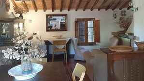 A rustic dining area with exposed wooden beams, a chandelier, and a table with a vase of flowers. - Villa Mulinello, secluded, panoramic view over Montepulciano valley. (torrita di siena, fraz. montefollonico)