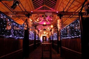 A corridor with wooden walls and ceiling, decorated with string lights and hanging ornaments. - Spacious Comfy 2BR flat (London)