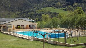 A swimming pool surrounded by a fence, with a building adjacent to it.
