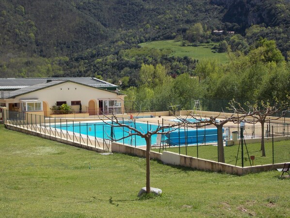 A swimming pool surrounded by a fence, with a building adjacent to it.
