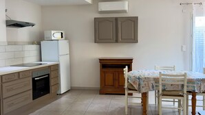 A modern kitchen with built-in appliances, a dining area with a table and chairs, and a window with curtains.