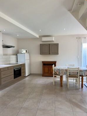 A modern kitchen with built-in appliances, a dining area with a table and chairs, and a window with curtains.