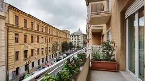A balcony with a row of potted plants and a view of a street with parked cars and buildings. - Lovely flat next to St. Peter's C. (Roma)