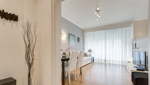 A modern living room with a dining area, wooden flooring, a TV, and a decorative vase. - Lovely flat next to St. Peter's C. (Roma)