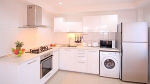 A modern kitchen with white cabinets, a stainless steel refrigerator, a microwave, a dishwasher, and a gas stove. - Blue Wave Samui Bophut (Koh Samui)