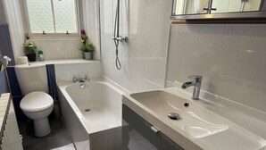 A modern bathroom with a bathtub, toilet, and sink. - Charming Morningside Flat in Edinburgh (Edinburgh)