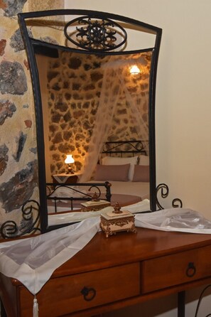 A wooden dresser with a mirror, a bed with a canopy, and a stone wall. - Stone villa shared pool & seaview, 1bedrooms, wifi, bbq (Astratigos)