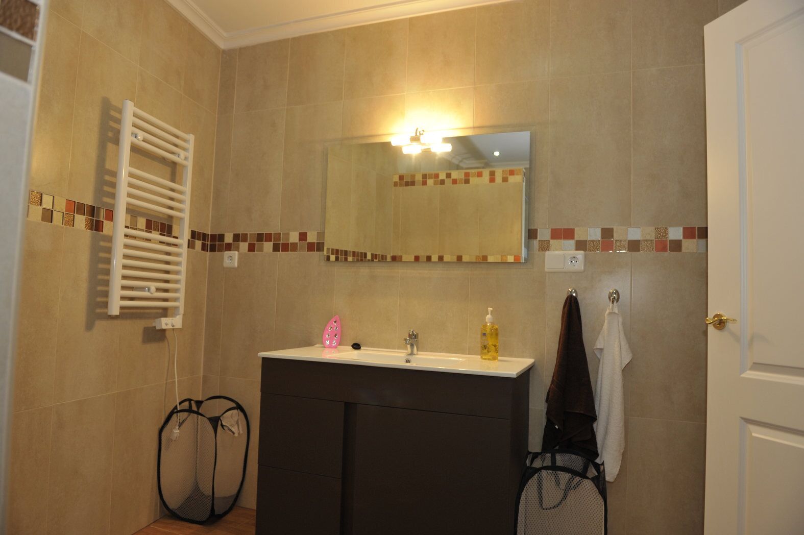 Un baño con lavamanos, espejo, toallero y cortina de ducha.