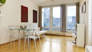Un salón moderno con comedor, ventanas amplias y vistas a la ciudad.