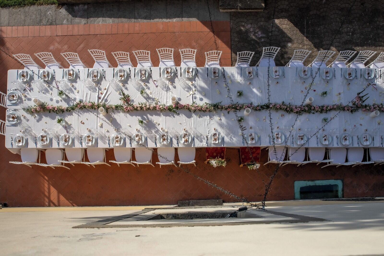 A dining area with white tables and chairs, decorated with floral garlands and small flower arrangements.